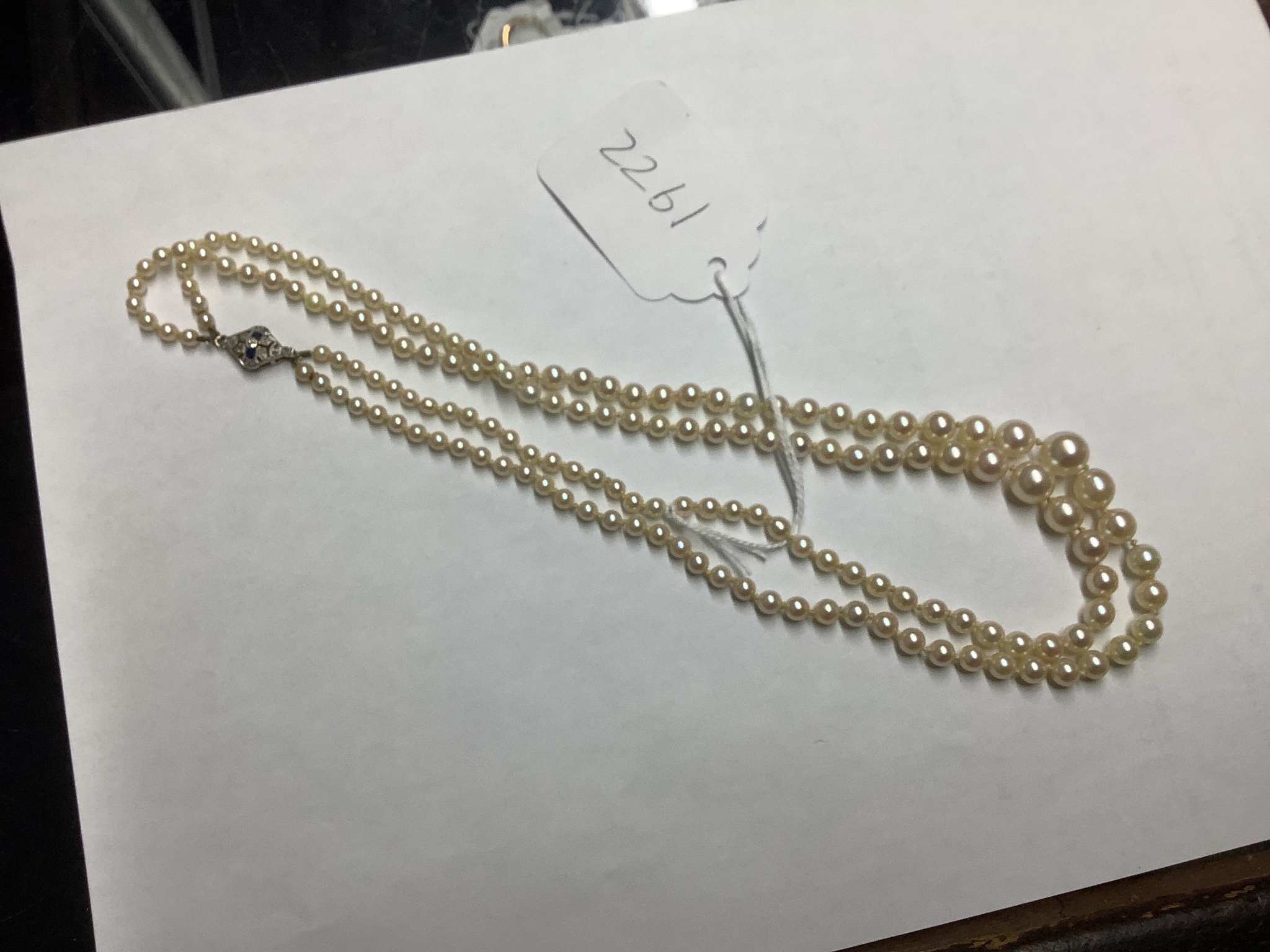 A double strand graduated cultured pearl necklace, with white metal (18ct poincon mark), sapphire and diamond set clasp signed Lacloche Freres and numbered 3763, 46cm, gross weight 33.8 grams